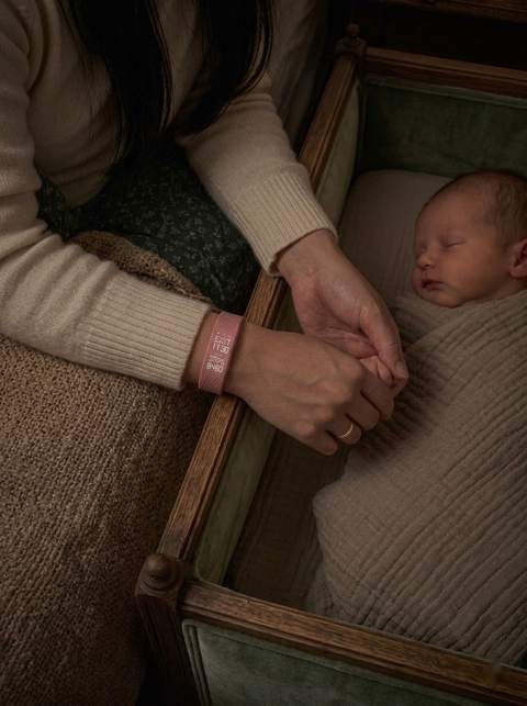 Bébé endormi, la main de maman avec le bracelet rose